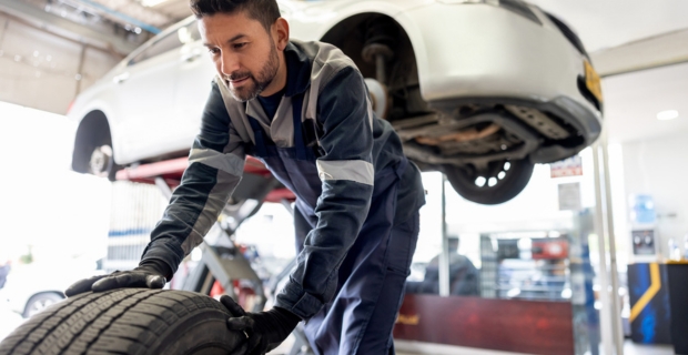 Un mécanicien déplace un pneu alors qu’il change les pneus d’une voiture dans son garage. 